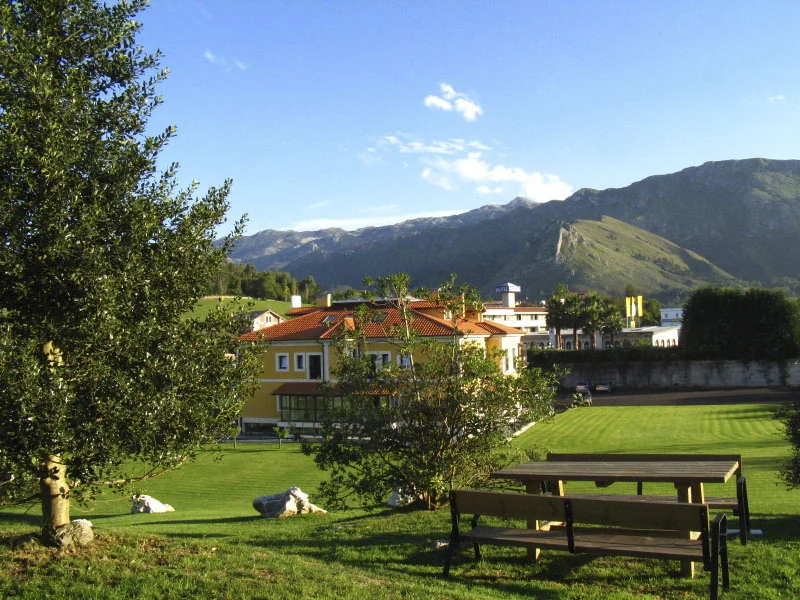 Jardín de la finca con mesas de madera y vistas a la sierra