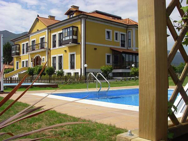 Fachada amarilla del hotel junto a la piscina exterior